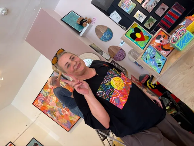 A guest smiling beside the colourful artworks on the gallery wall at BLAK LUB opening night