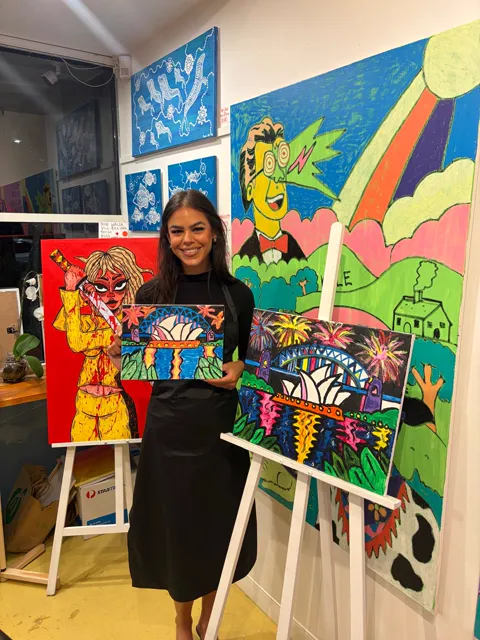 A guest proudly holding her finished harbour painting beside the artist’s painting