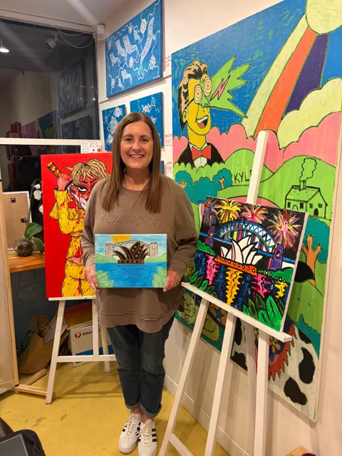 A guest holding her finished painting of the Sydney Opera House