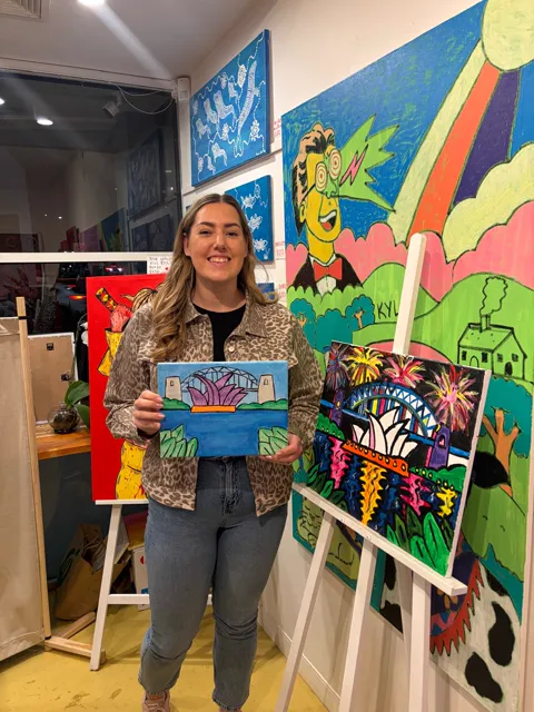 A guest smiling with her finished harbour painting