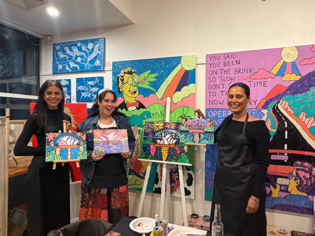 Guests with their finished harbour paintings in front of the gallery walls